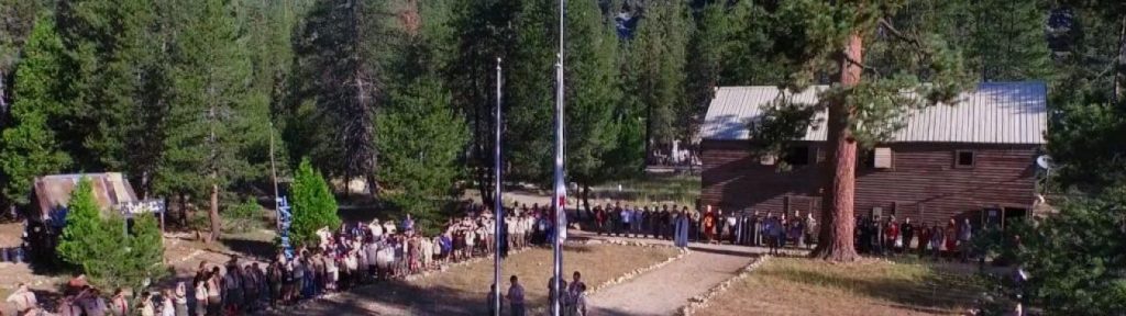 Parade grounds amid Flag ceremony with full population of camp at attention.